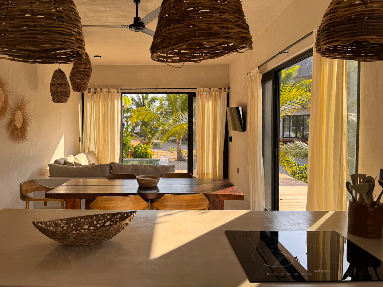 Cocina y comedor de parota con lámparas tejidas y puertas abiertas hacia la terraza